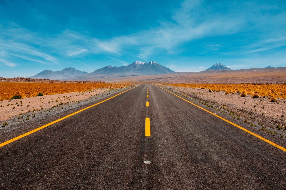 Route droite traversant un paysage vers les montagnes